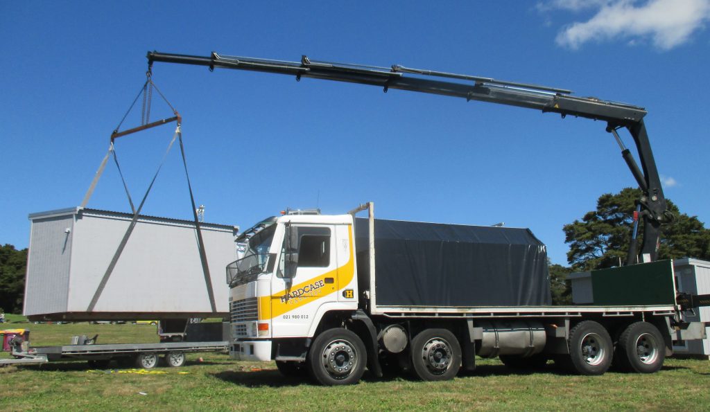Our Volvo truck and Hiab crane has a huge reach and lifts cabins as easily as containers as seen here. We can hire our truck and Hiab crane for your needs especially in west Auckland, Massey, Hobsonville, New Lynn.